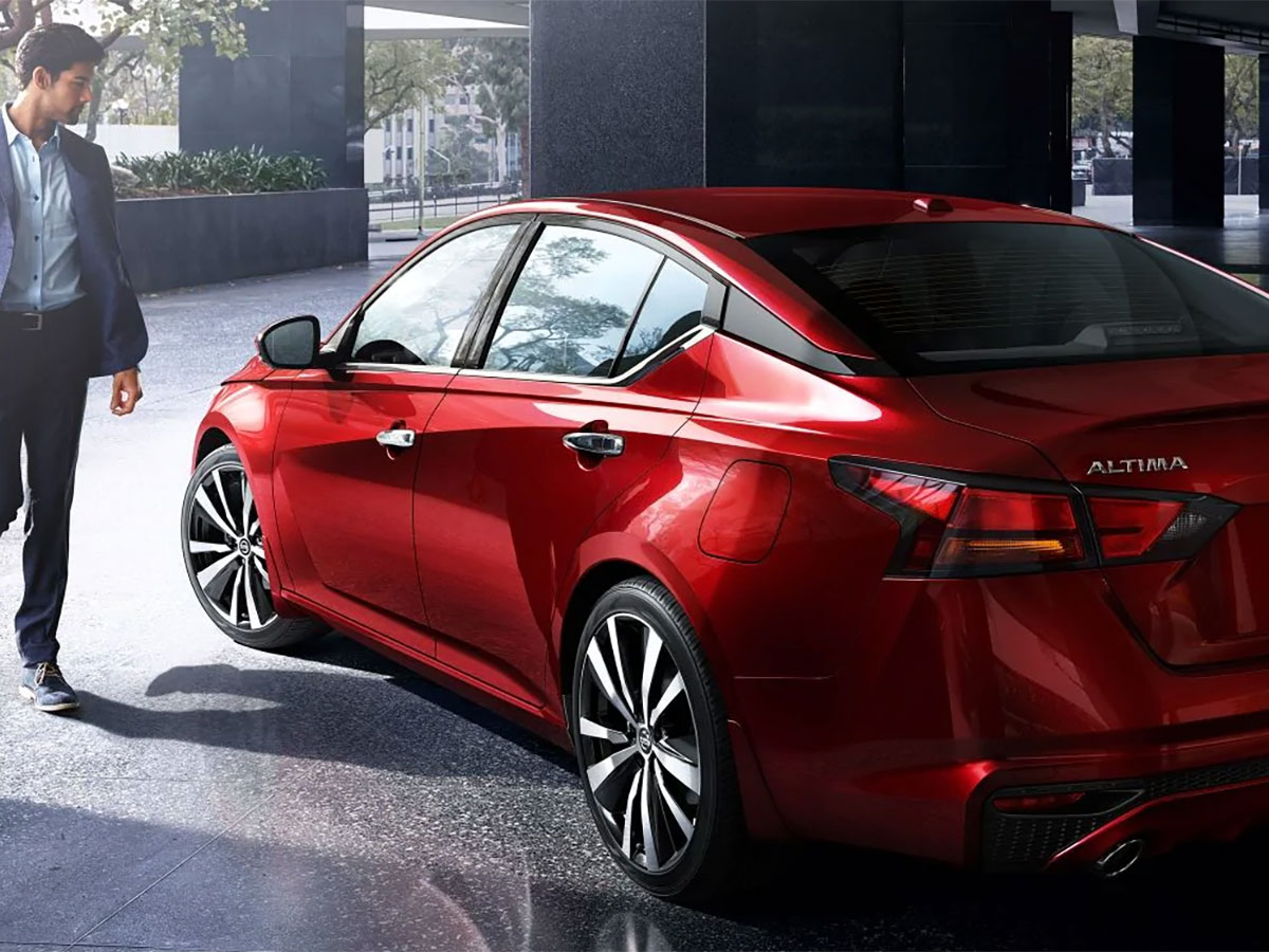 Man standing beside a red Nissan Altima