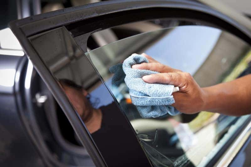 Hand cleaning a car window with a microfiber cloth