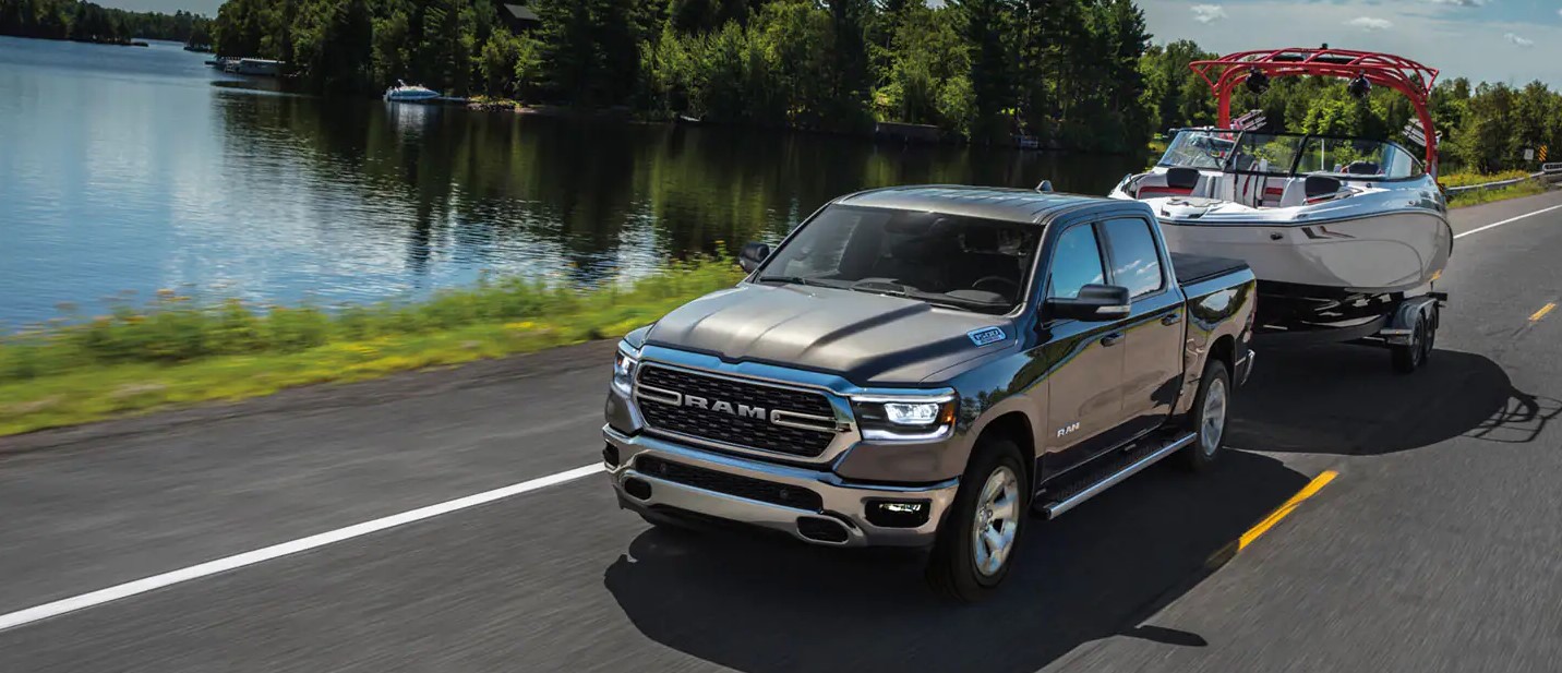 A gray RAM 1500 EcoDiesel truck towing a boat near the shore of a lake