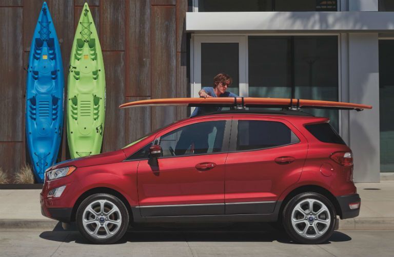 side view of a red 2021 Ford EcoSport with a surfboard on its roof rack