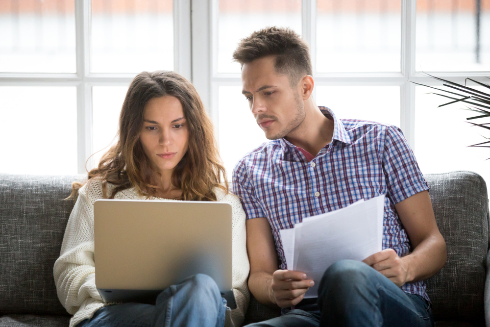 couple comparing information while intensely staring at a laptop