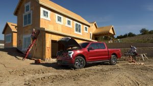 side view of a red 2022 Ford F-150 Lightning with its front trunk open