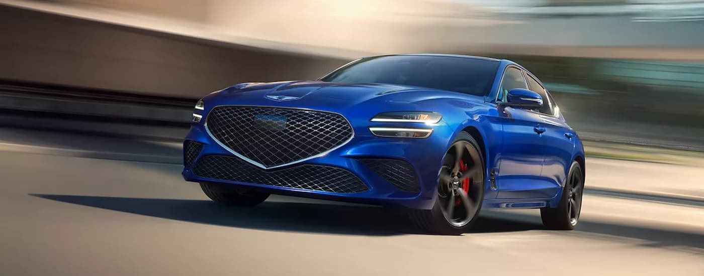Blue 2026 Genesis G70 driving down an open road.