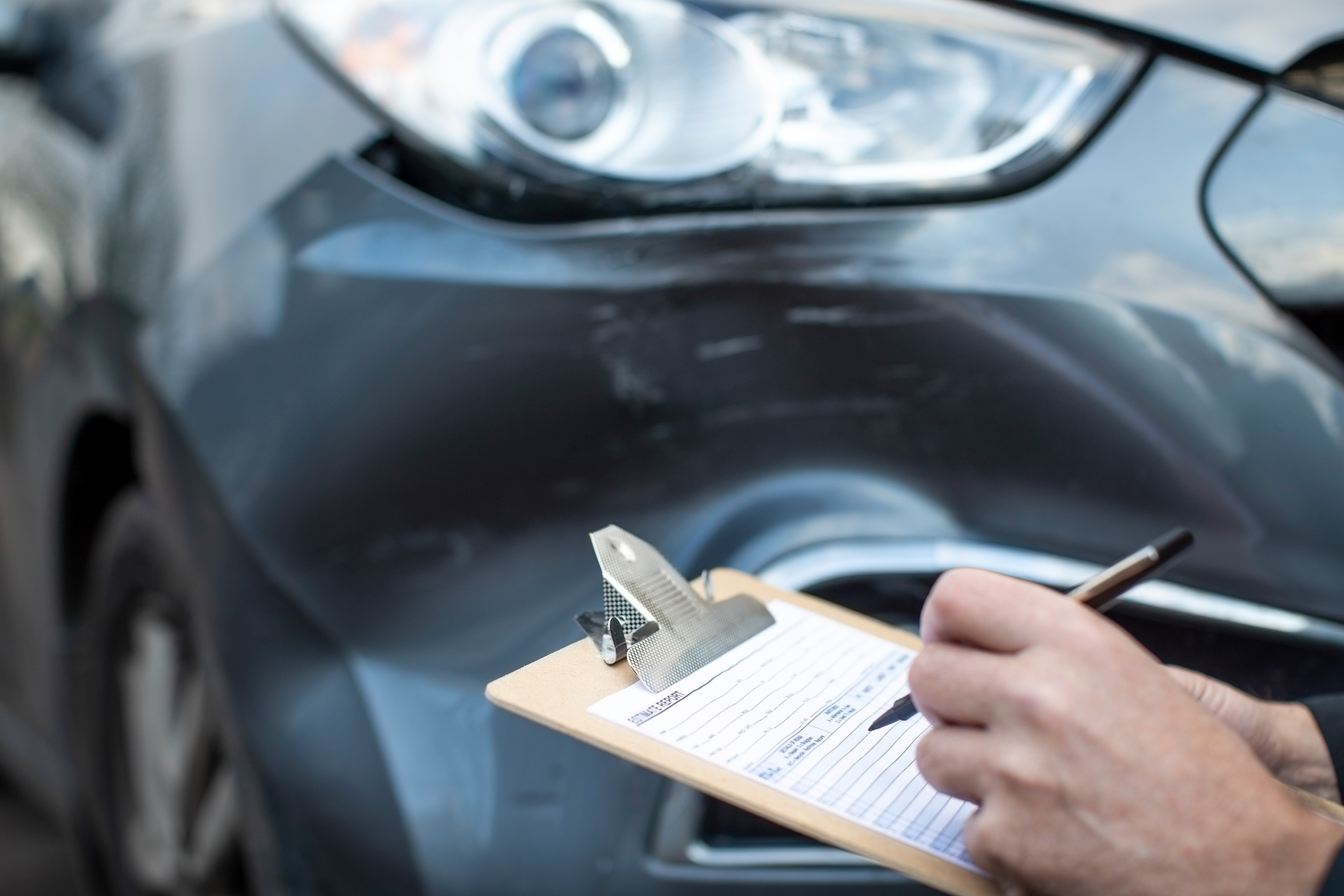 A person writes on a clipboard while inspecting a 