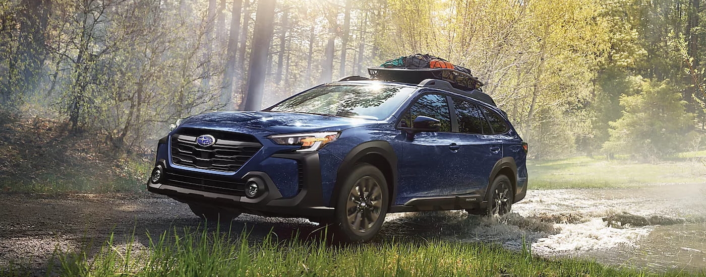 "A blue 2024 Subaru Outback Onyx Edition XT off-roading through the woods.