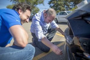 two Ford engineers placing a strip of duct tape on the front of a 2018 Ford Mustang