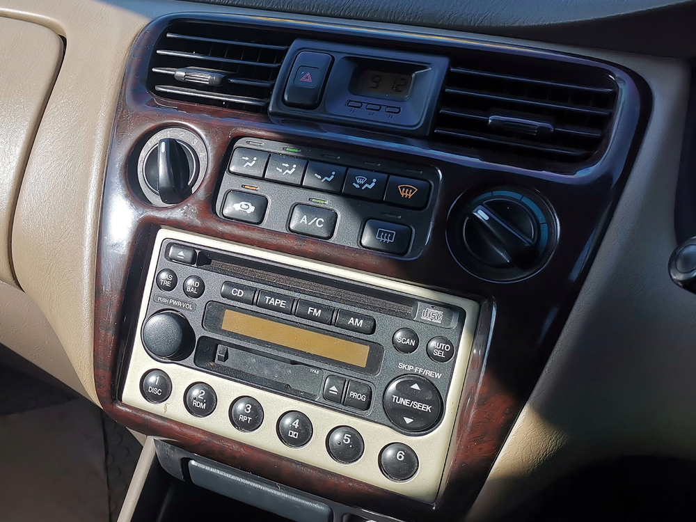 A classic car’s center console featuring an integrated CD player, cassette player, and AM/FM radio, exemplifying a multifunctional audio system.