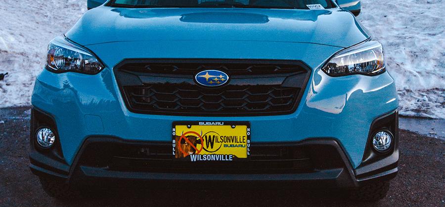 Front of a blue Subaru Crosstrek with headlights on