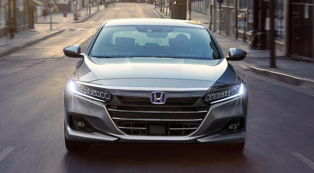A silver 2021 Honda Accord Hybrid is shown from the front on a city street.