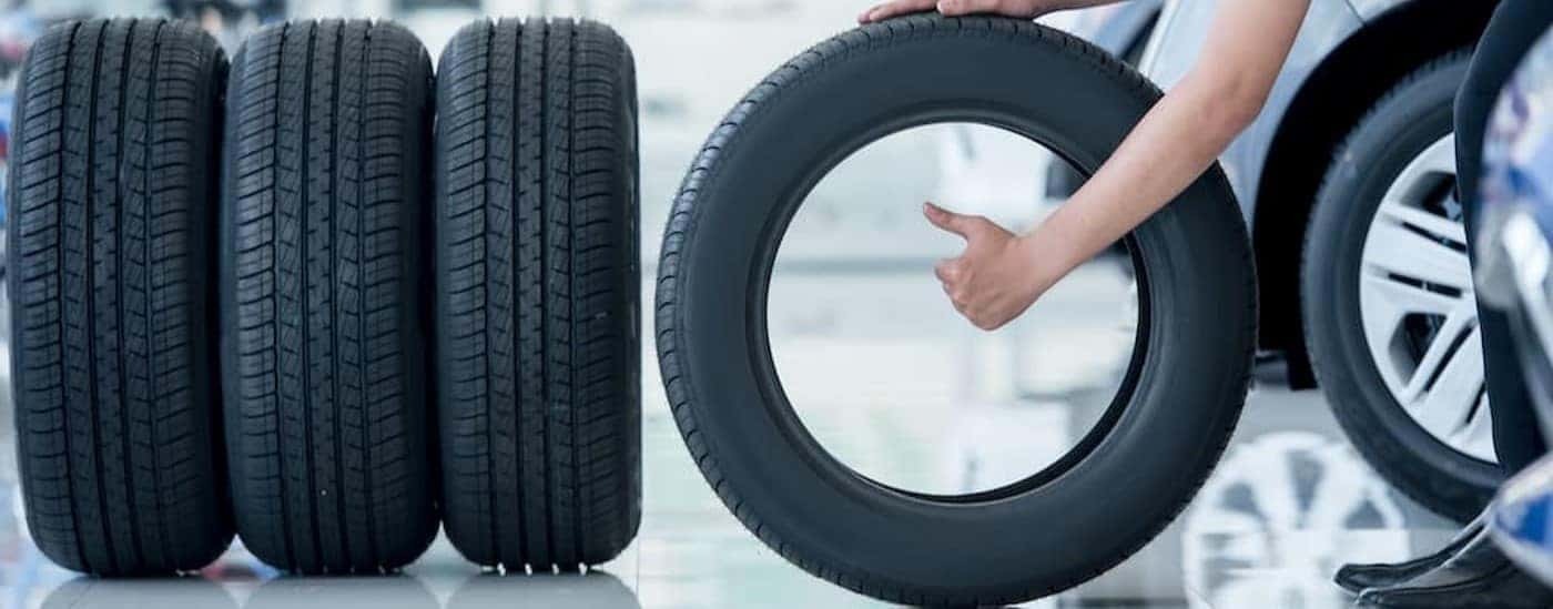 Several tires are lined up next to a mechanic giving a thumbs up.