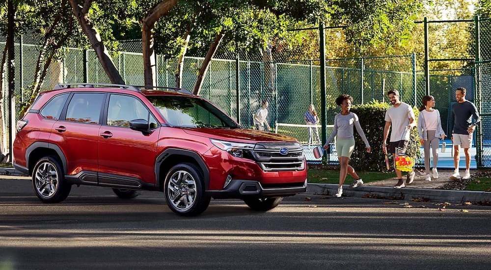Group of people walking towards a red 2026 Subaru Forester.