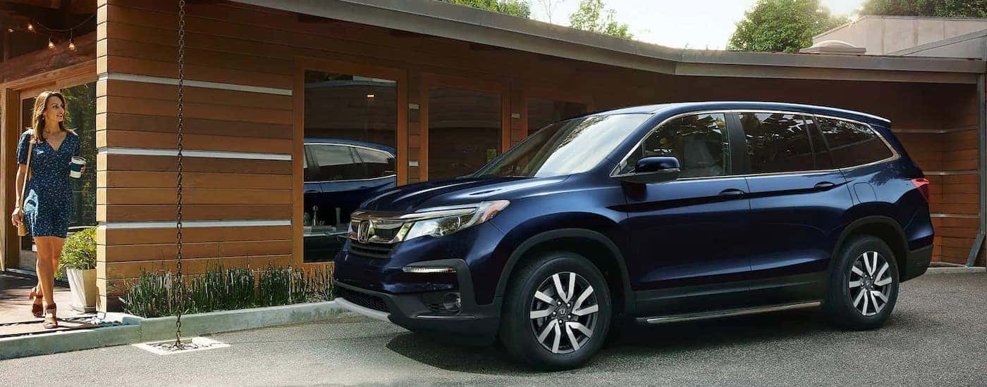 A blue 2022 Honda Pilot is shown from the side parked in a home driveway.