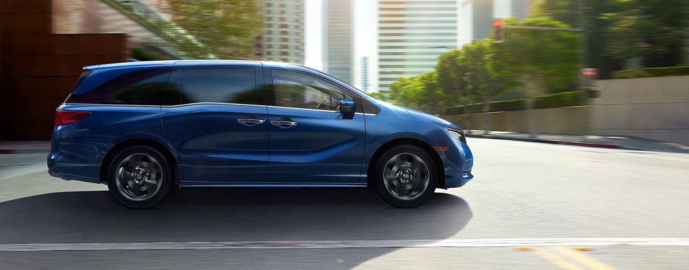 Blue 2021 Honda Odyssey Elite is driving on a city street