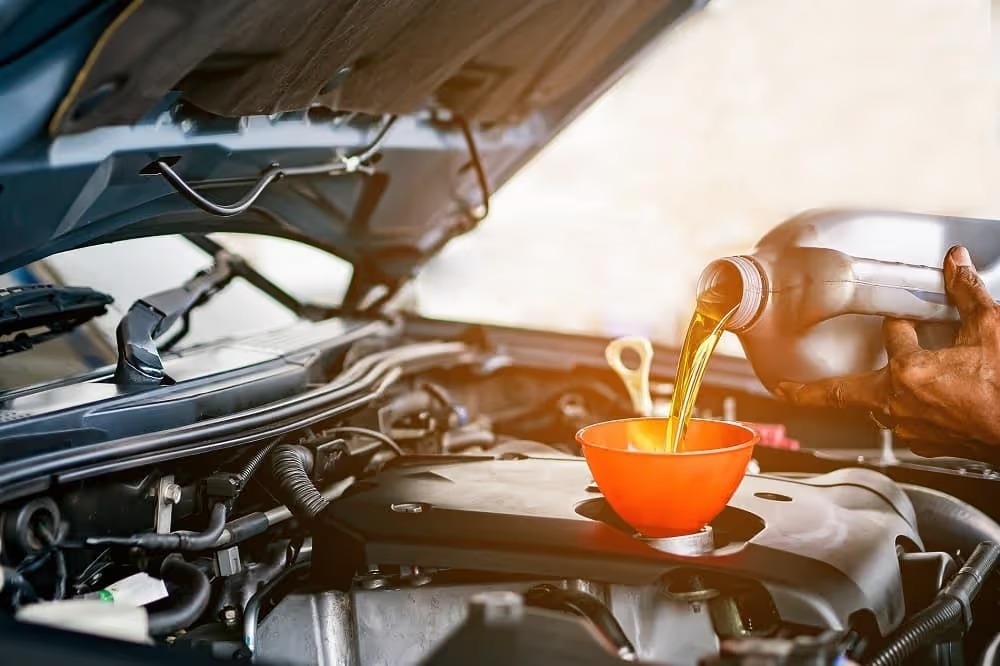 Fresh motor oil being poured into an engine through a funnel