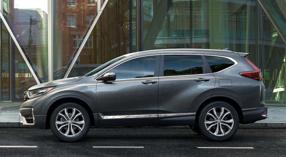 A popular Honda SUV, a grey 2021 Honda CR-V is parked in front of large glass windows.