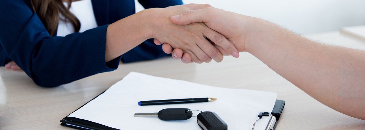 Woman shaking mans hand over a car contract clipboard with car keys