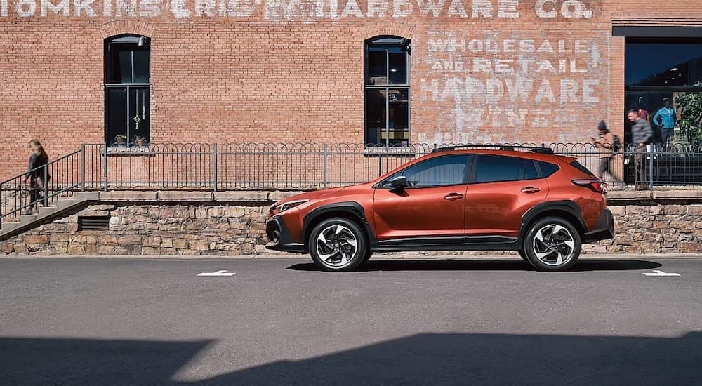 An orange 2024 Subaru Crosstrek for sale near Poughkeepsie is shown parked near a store.