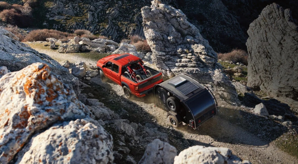 Orange 2025 Nissan Frontier PRO-4X towing a trailer off-road