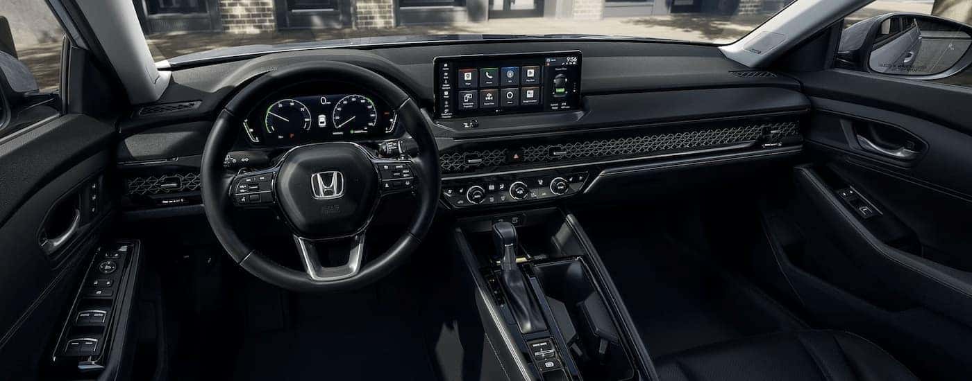 The black interior of a 2023 Honda Accord shows the steering wheel and center console.