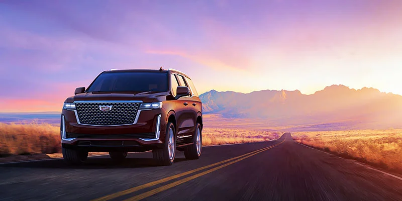 black 2023 Cadillac Escalade driving on a road with mountains in the background