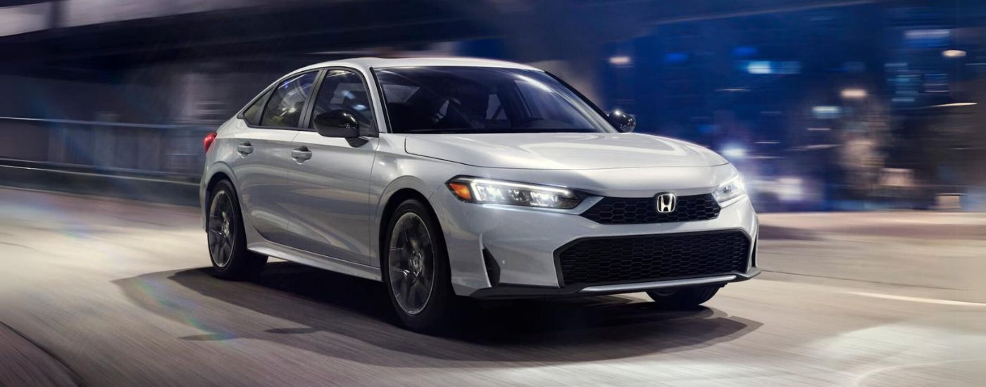 A silver 2026 Honda Civic driving on a highway at night