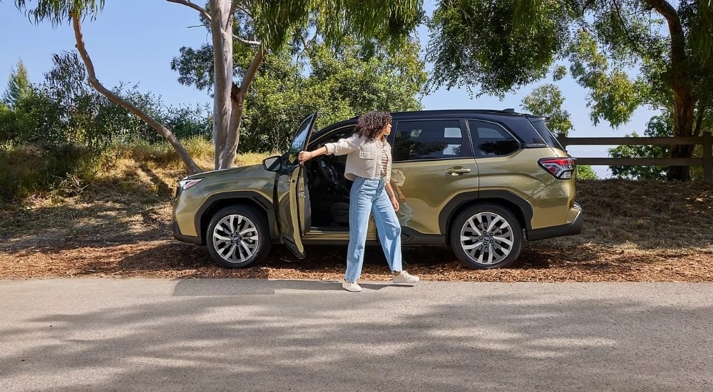 A green 2025 Subaru Forester Hybrid parked near a fence.