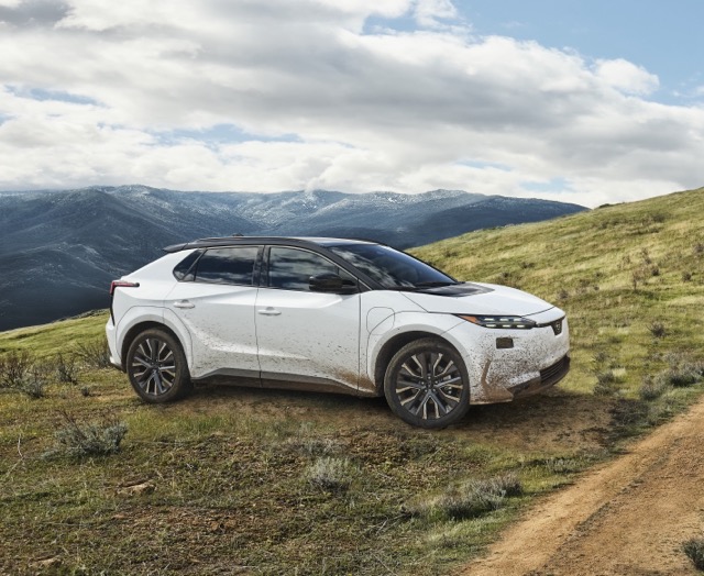 A static image of a white 2027 Subaru Solterra parked on a grassy hill.