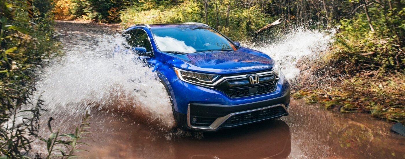 Blue 2021 Honda CR-V Touring is shown driving through a puddle
