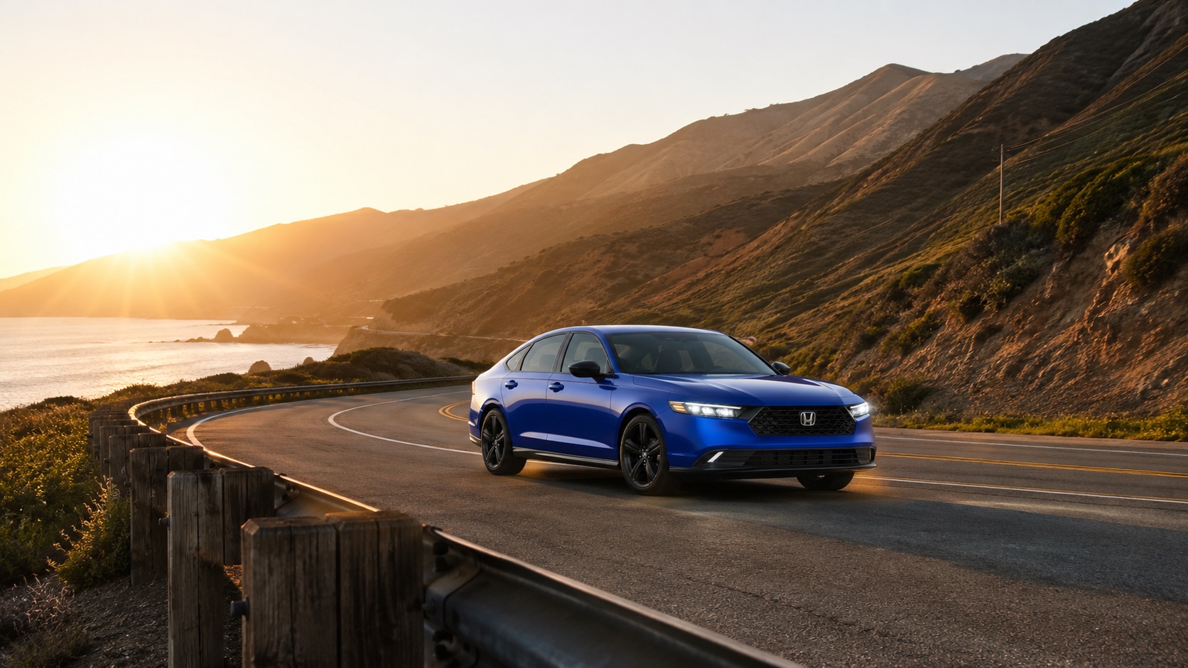 A blue 2026 Honda Accord driving along a California coastal highway at sunset, capturing its sporty profile and dynamic performance with ocean and mountain views.