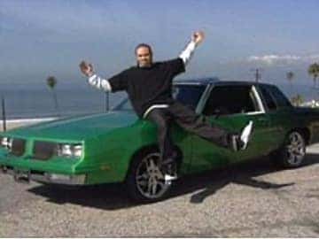 Man jumping beside a customized green car