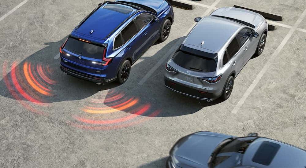 A blue 2025 Honda CR-V Sport Touring Hybrid reversing out of a parking spot.