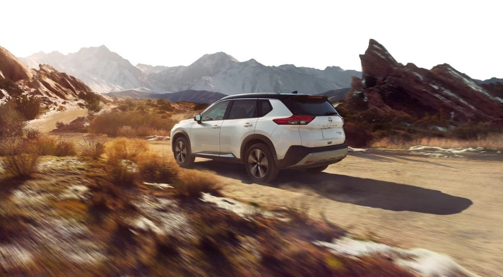 White 2021 Nissan Rogue driving down a trail with bikes on the roof