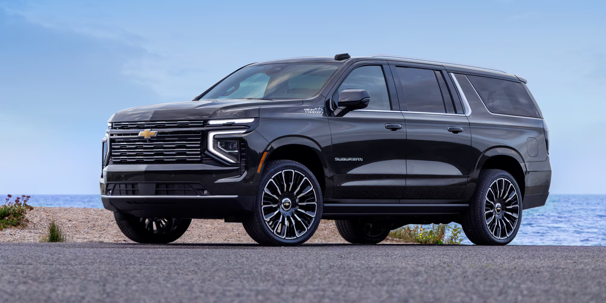 A black suv sitting parked in front of some water.