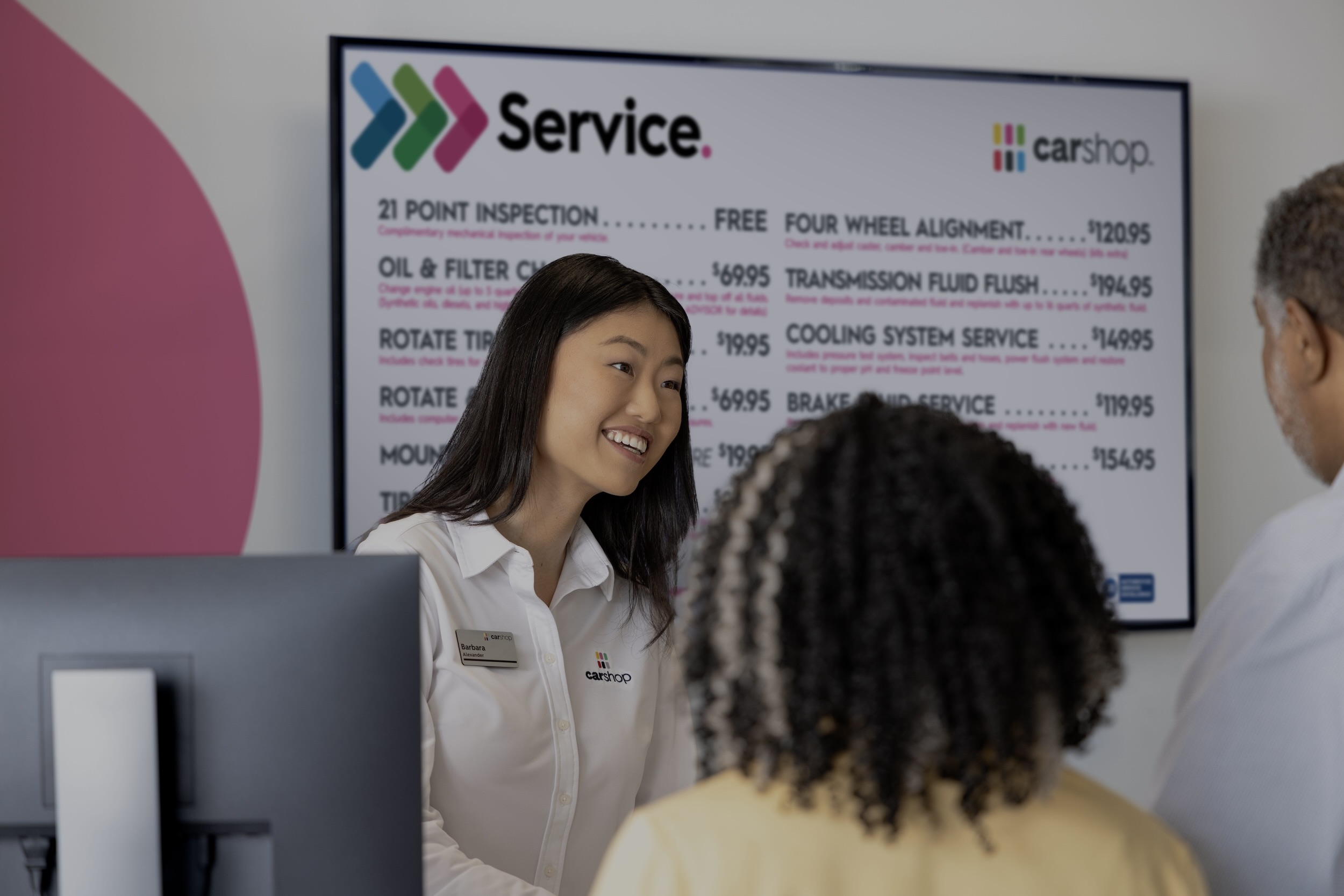 Associate smiling with clients in front of service menu