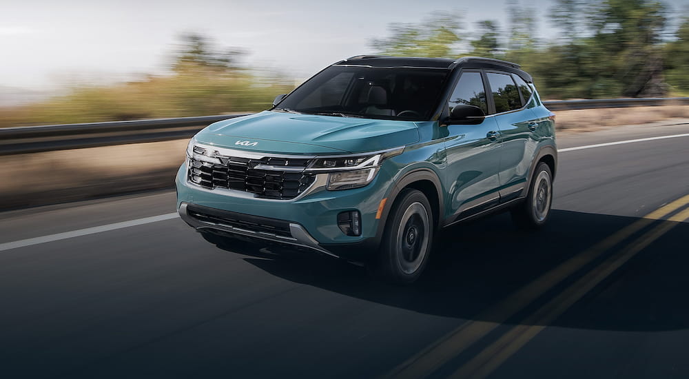 Blue 2026 Kia Seltos driving down a road.