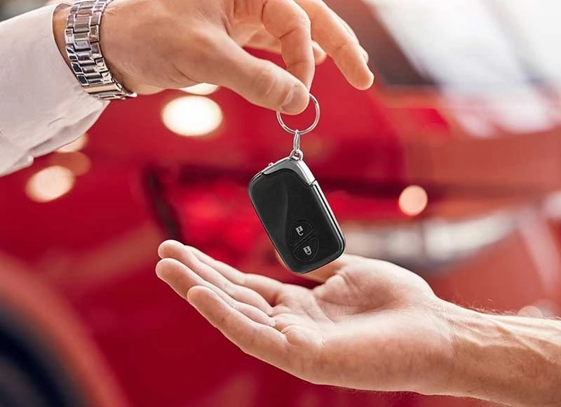 A person handing over a car key fob to another person