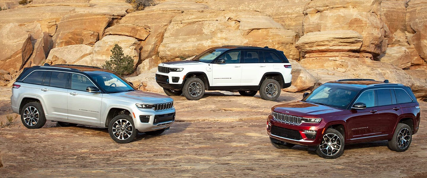 Three jeeps sitting parked on top of a rock.