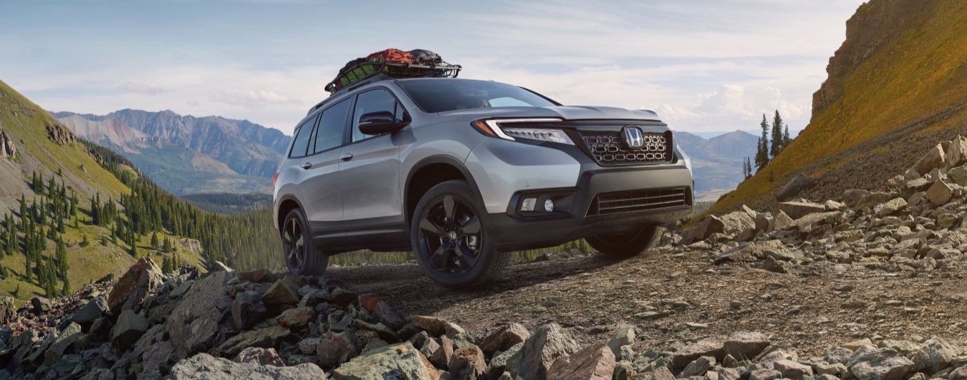 White 2020 Honda Passport driving off-road up a hill.