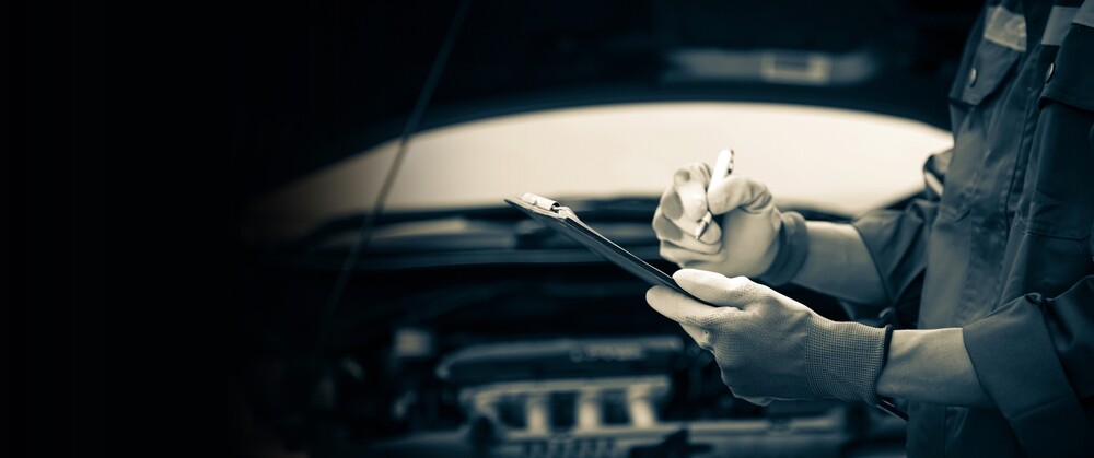 Car mechanic writing notes on a clipboard.