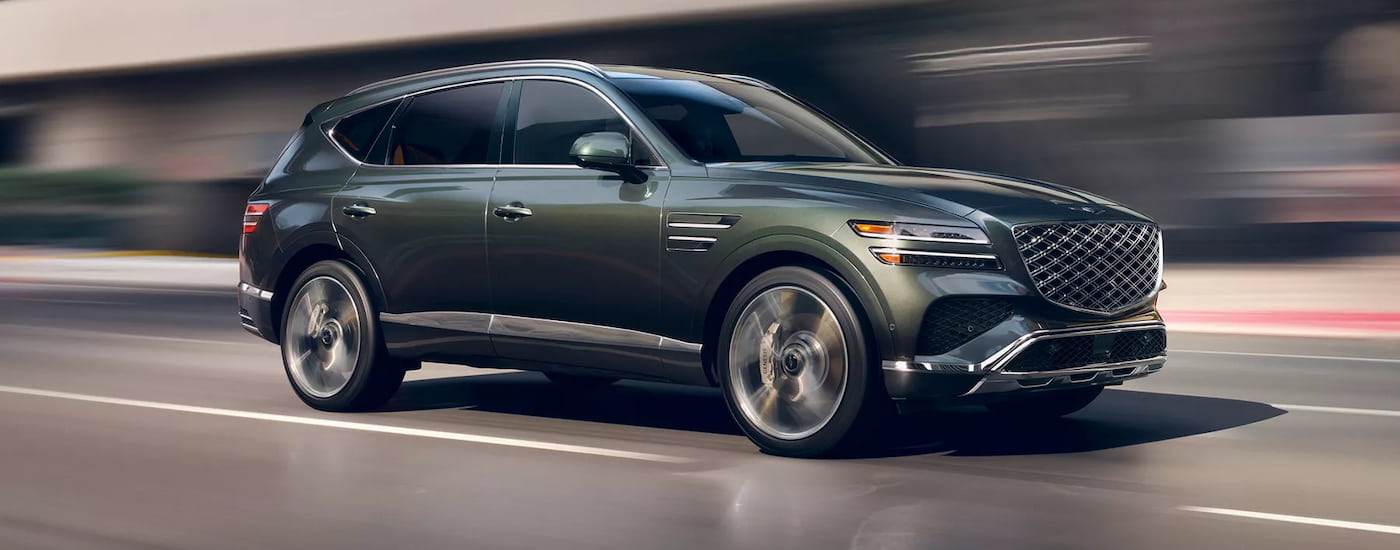 Green 2025 Genesis GV80 for sale near me driving down a road.