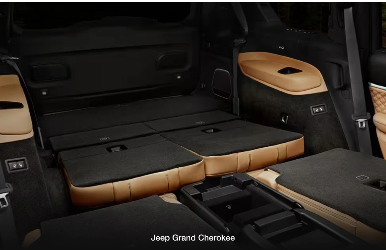 Interior view of a Jeep Grand Cherokee with its rear seats folded down, showing a spacious cargo area.