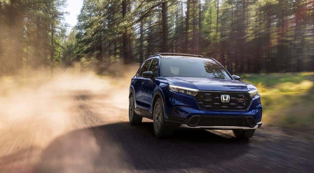 A blue 2026 Honda CR-V Hybrid driving on a dirt road