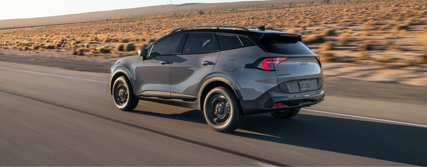 Grey 2026 Kia Sportage driving down an open road