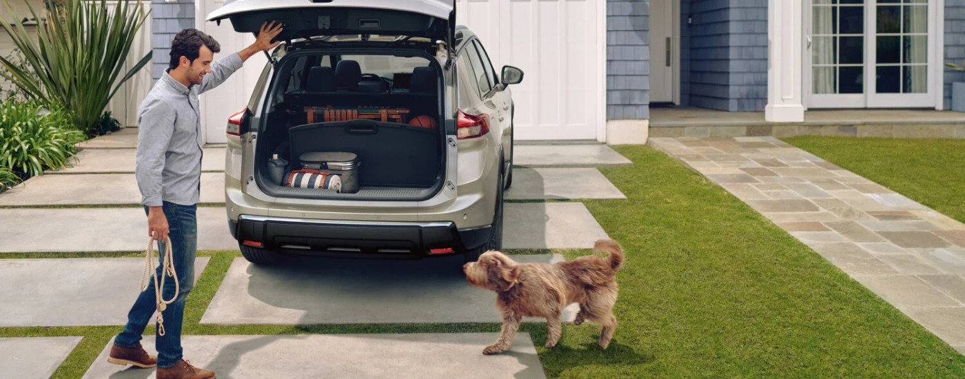 Tan 2026 Nissan Rogue in a driveway with a man and dog