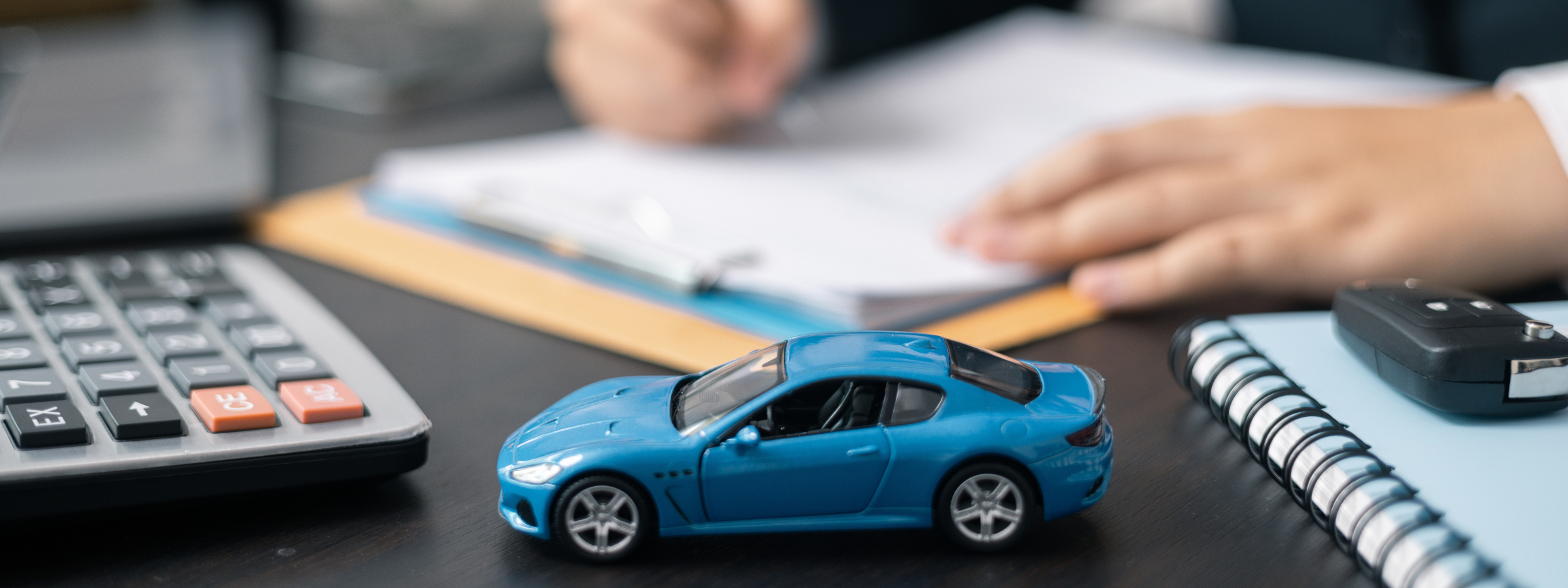 Customer signing paperwork beside a toy car and calculator