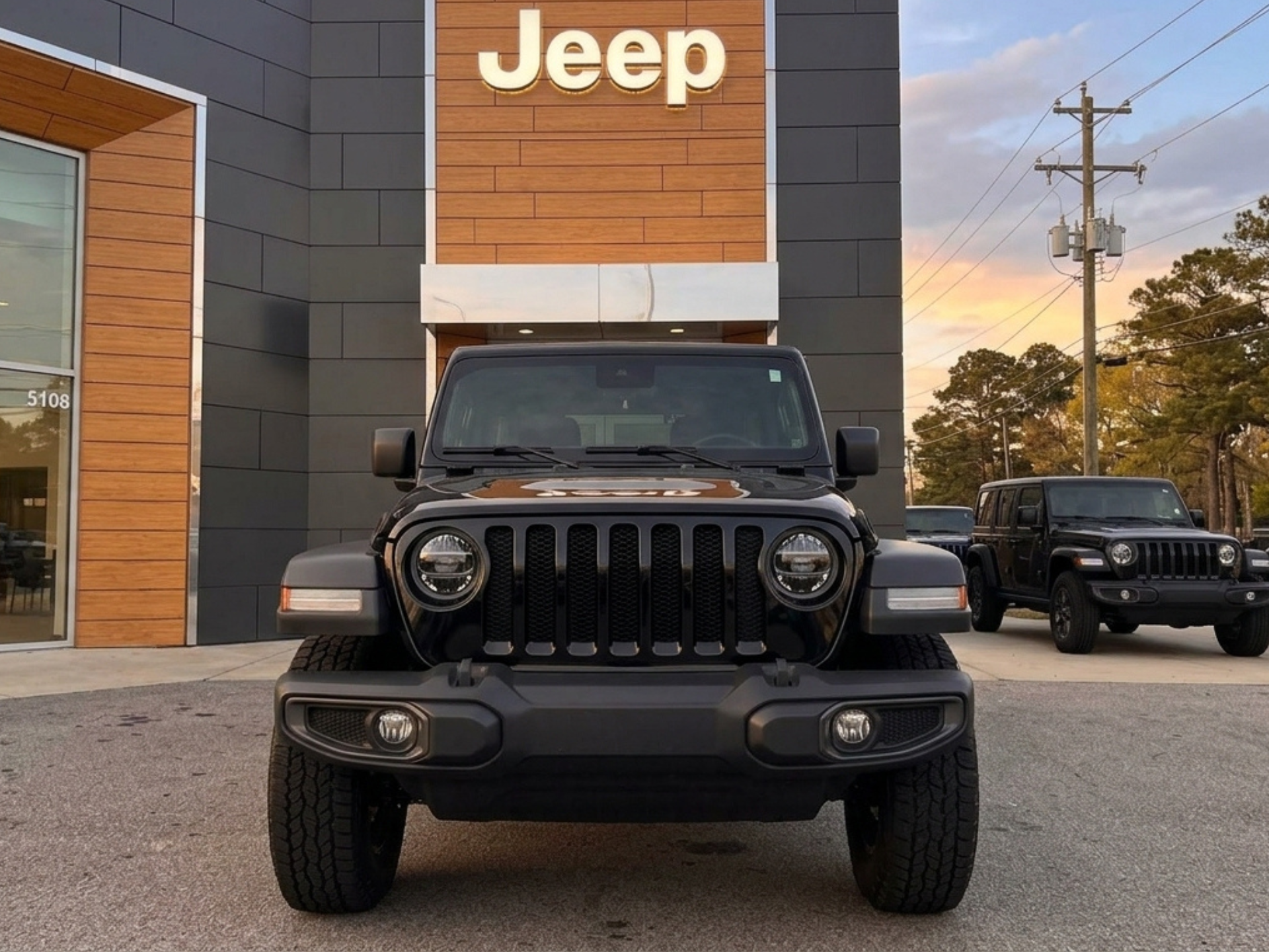 Used black jeep wrangler in front of the Westgate Jeep showroom at sunset.