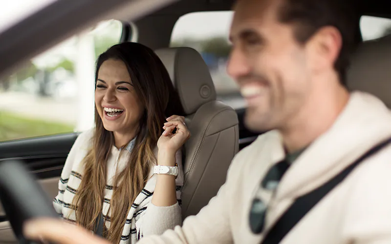 a couple smiling while driving a car