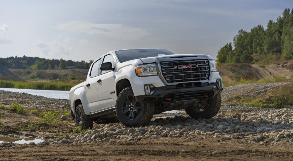 A white 2021 GMC Canyon AT4 is shown parked off-road.