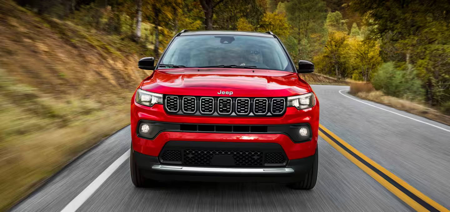 A red Jeep Compass drinf on a road.