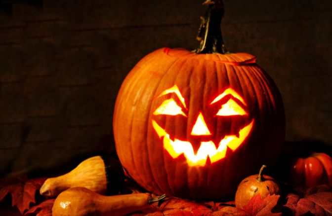 Lit Up Jack-O-Lantern on a Table with Halloween Gourds